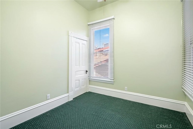 spare room featuring baseboards and dark colored carpet