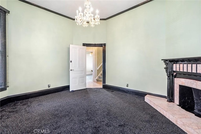 unfurnished living room featuring a towering ceiling, ornamental molding, a tiled fireplace, baseboards, and a notable chandelier
