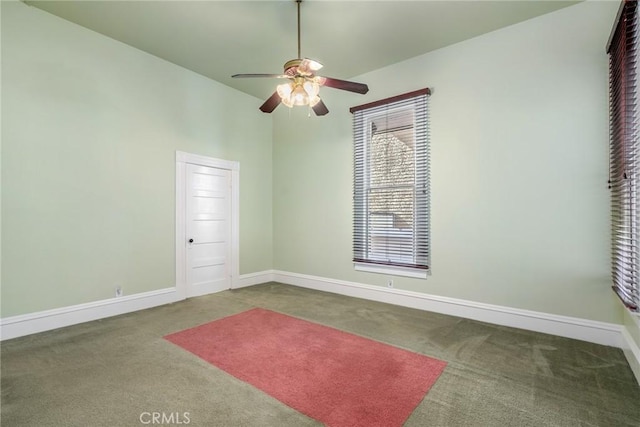 carpeted empty room with ceiling fan, a high ceiling, and baseboards