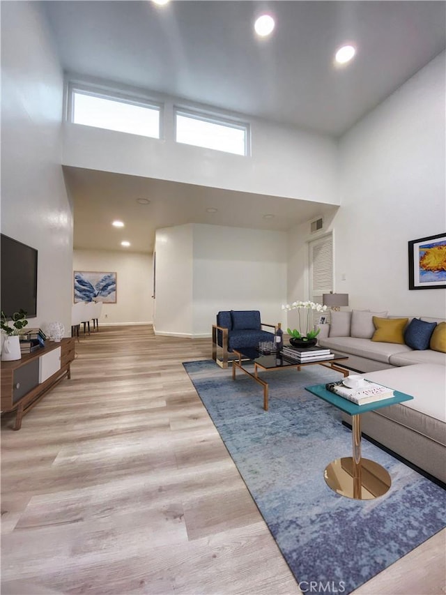 living area featuring a wealth of natural light, wood finished floors, and a towering ceiling