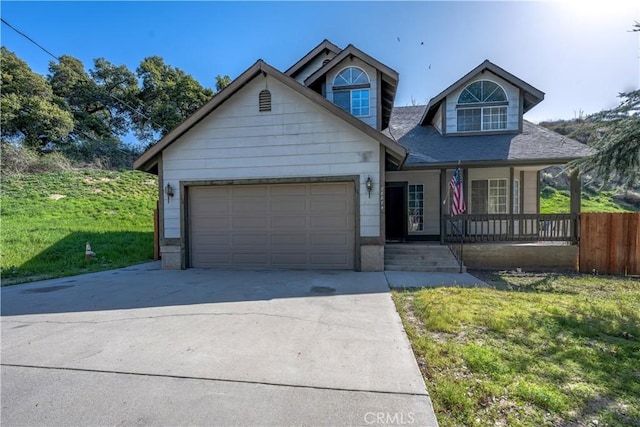 view of front of home featuring a front yard, an attached garage, covered porch, fence, and driveway