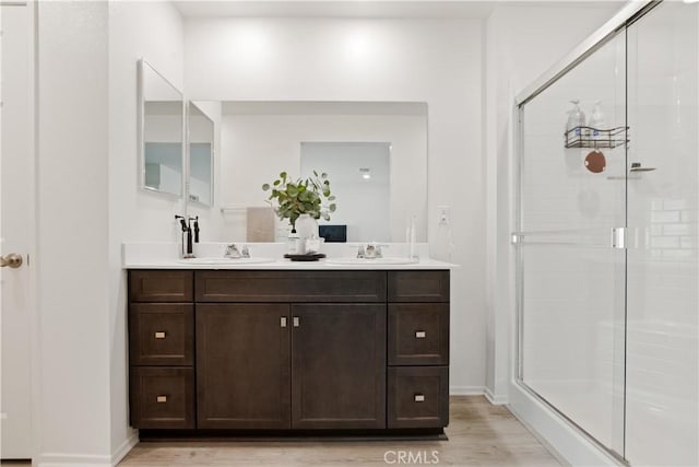 bathroom featuring a shower stall, a sink, and wood finished floors