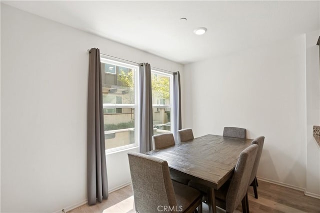 dining space featuring light wood finished floors and baseboards