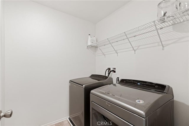 laundry room with washing machine and clothes dryer, baseboards, and laundry area