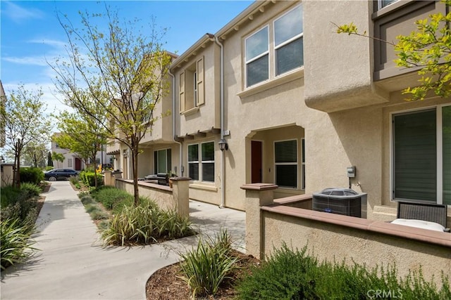 view of home's exterior with central AC unit, fence, and stucco siding