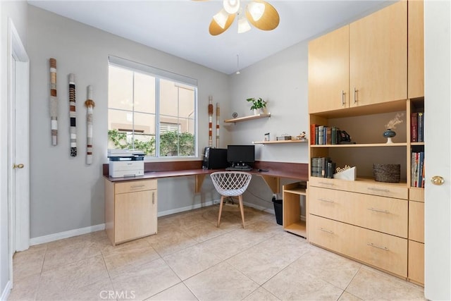 office with built in desk, ceiling fan, light tile patterned flooring, and baseboards