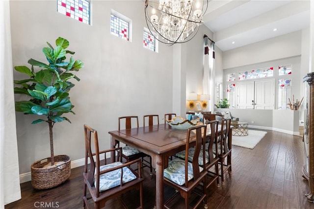 dining room featuring baseboards, a towering ceiling, dark wood-style flooring, and an inviting chandelier