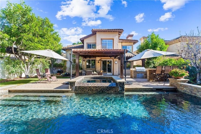 rear view of house with a patio area, an in ground hot tub, a tile roof, and exterior kitchen