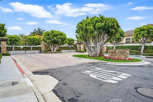 view of street featuring a gated entry, sidewalks, curbs, and a gate