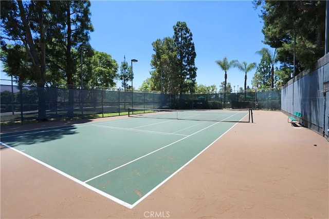 view of tennis court with community basketball court and fence