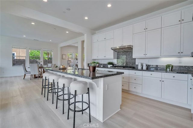 6014 Amora Dr, Chino Hills, CA 91709 - kitchen featuring a sink, a kitchen breakfast bar, dark stone countertops, and under cabinet range hood