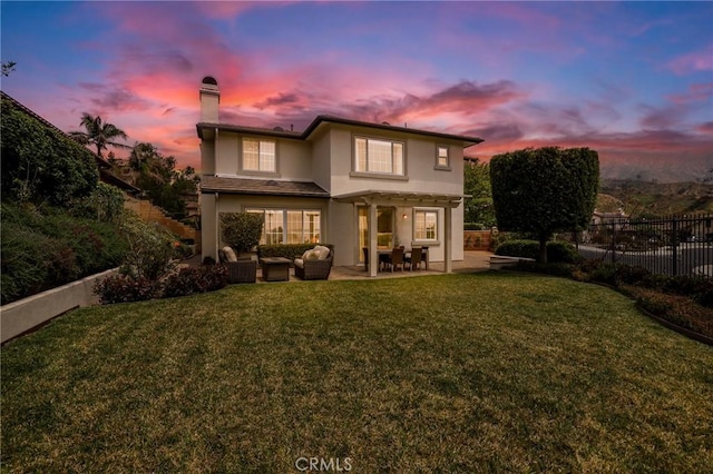 608 Chaparral Ct, Altadena, CA 91001 - back of property at dusk featuring a lawn, stucco siding, a chimney, and fence