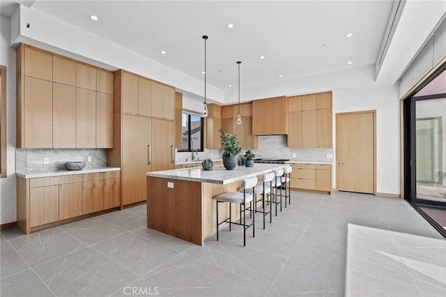 kitchen with light brown cabinets, a kitchen breakfast bar, decorative backsplash, and modern cabinets
