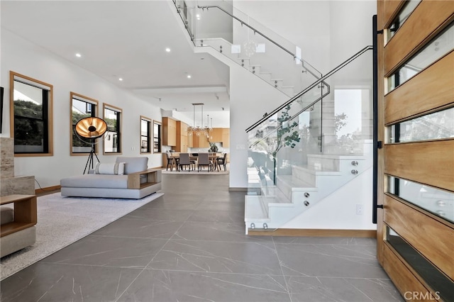 interior space featuring recessed lighting, marble finish floor, a towering ceiling, baseboards, and a notable chandelier