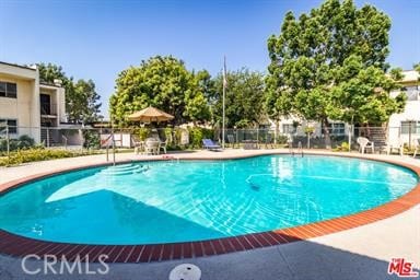 community pool with fence and a patio