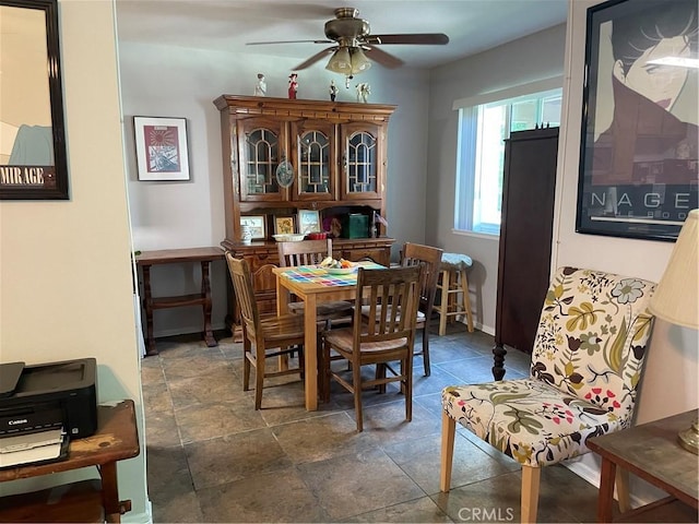 dining area with stone finish flooring, baseboards, and a ceiling fan