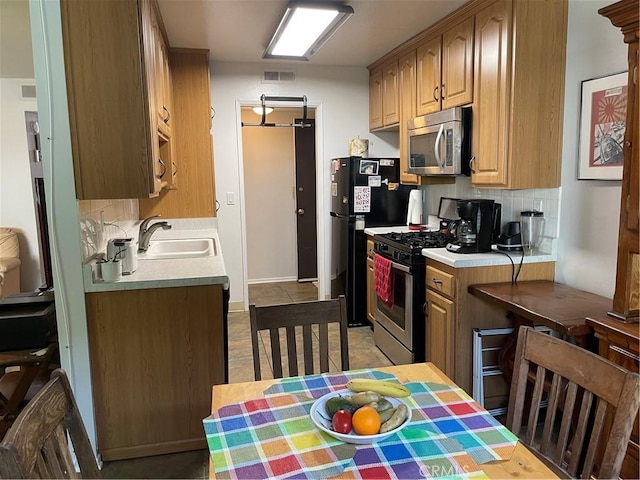 kitchen featuring tasteful backsplash, light countertops, visible vents, appliances with stainless steel finishes, and a sink