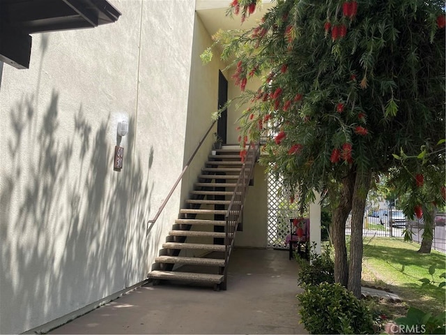 exterior space featuring a patio area, fence, stairway, and stucco siding