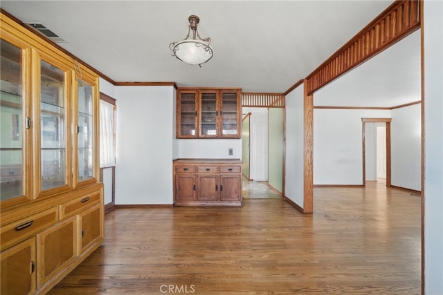 dining space featuring visible vents, ornamental molding, baseboards, and wood finished floors