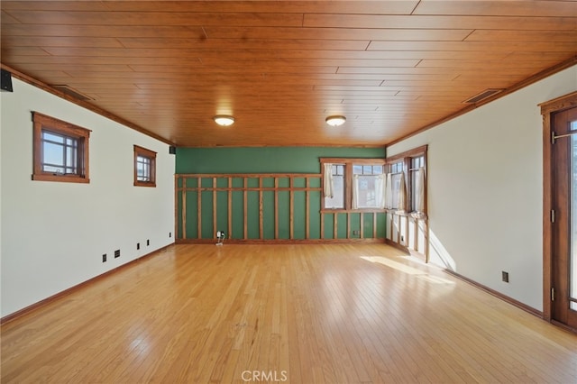 unfurnished room featuring ornamental molding, wood-type flooring, baseboards, and visible vents