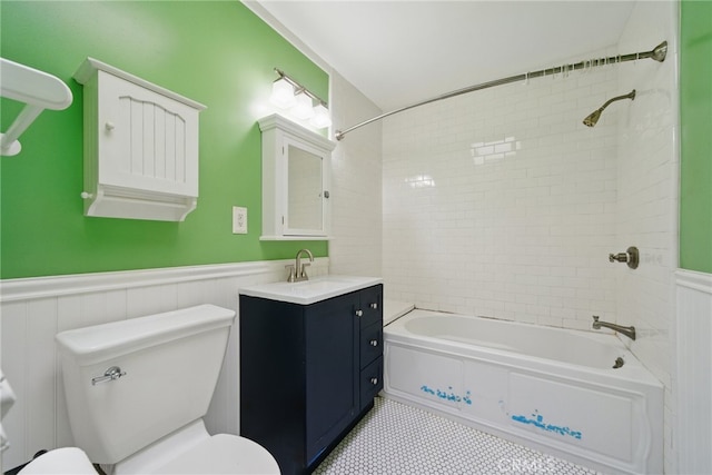 bathroom with washtub / shower combination, vanity, wainscoting, and toilet