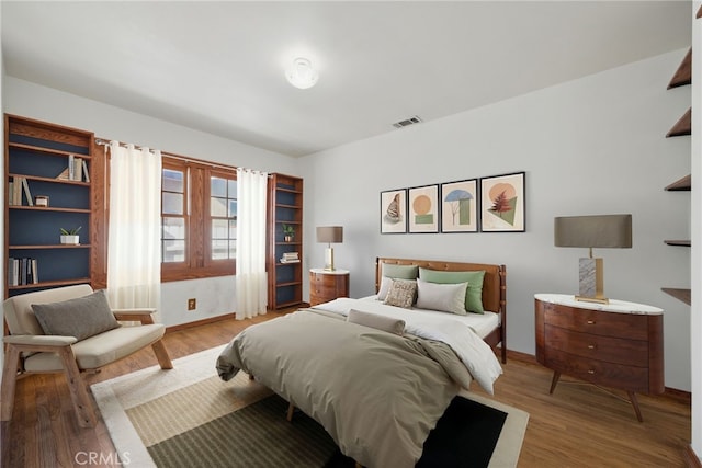 bedroom featuring visible vents, light wood-style flooring, and baseboards