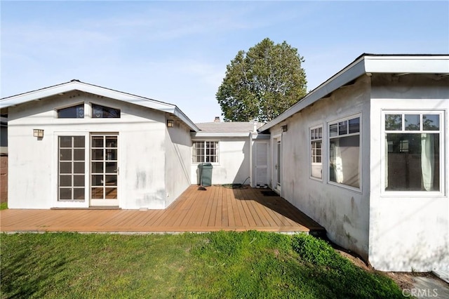 back of property with a yard, a deck, and stucco siding