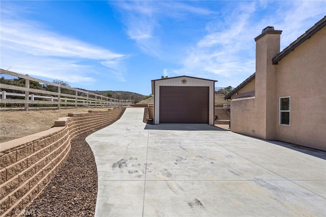 exterior space featuring a garage, driveway, an outbuilding, and fence