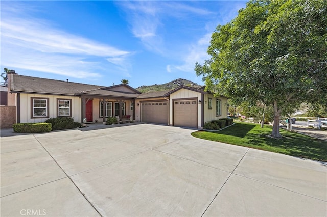view of front of home featuring an attached garage, board and batten siding, driveway, covered porch, and a front yard
