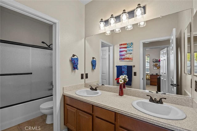 bathroom featuring enclosed tub / shower combo, toilet, a sink, and double vanity