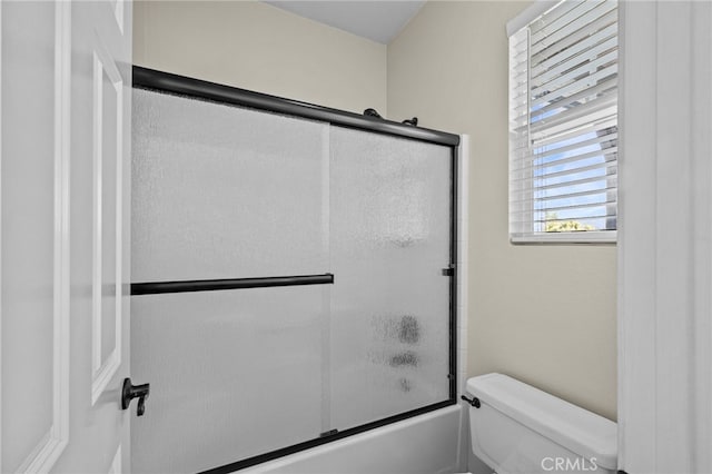 full bathroom featuring combined bath / shower with glass door and toilet