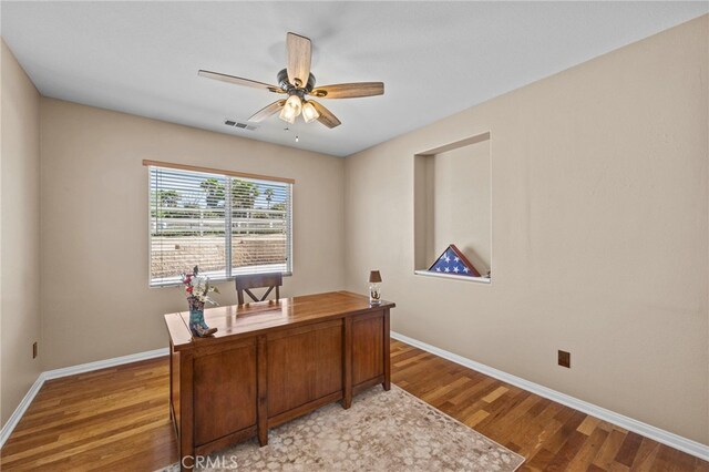 office space with light wood-type flooring, visible vents, a ceiling fan, and baseboards