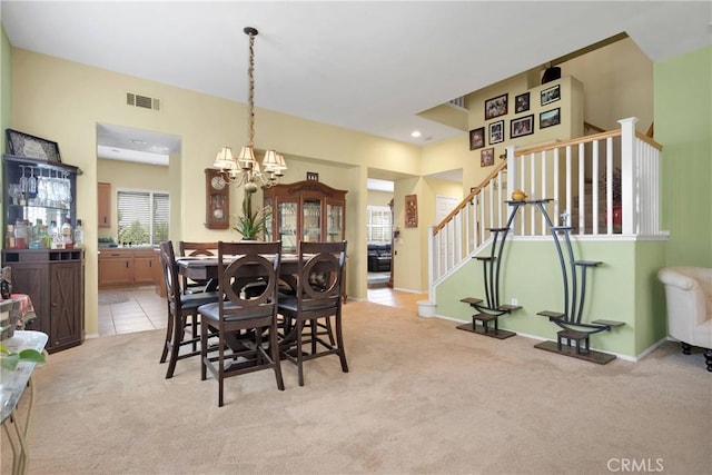 dining area with visible vents, stairway, an inviting chandelier, and light colored carpet