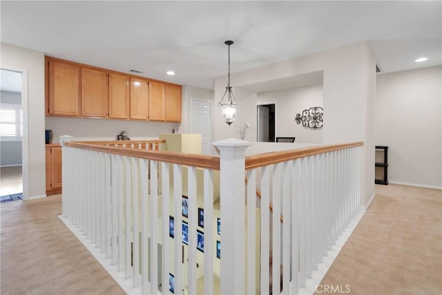 hallway featuring light carpet, baseboards, an upstairs landing, and recessed lighting