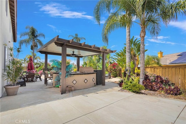 view of patio / terrace with outdoor dining space, a ceiling fan, fence, and exterior kitchen