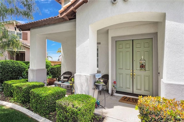 doorway to property featuring stucco siding and a tile roof