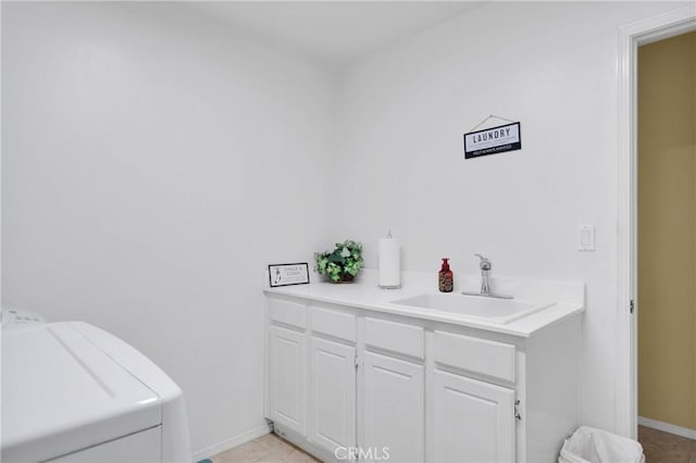 bathroom featuring washing machine and dryer, baseboards, and a sink