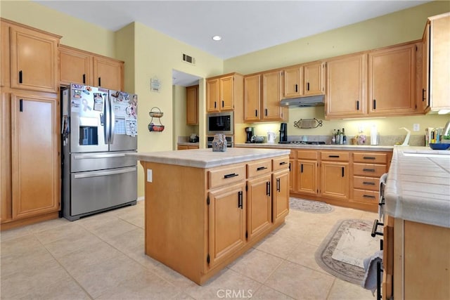 kitchen with a center island, under cabinet range hood, tile countertops, and stainless steel appliances