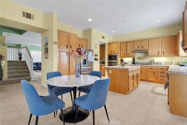 kitchen featuring light tile patterned floors, a kitchen island, under cabinet range hood, visible vents, and appliances with stainless steel finishes
