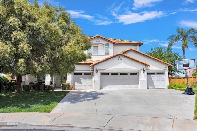 mediterranean / spanish house with a front yard, a tile roof, driveway, and stucco siding