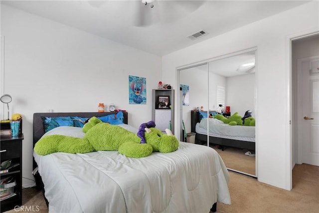 carpeted bedroom featuring visible vents, a closet, and a ceiling fan