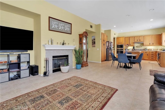 living room featuring a tile fireplace, light tile patterned floors, baseboards, and recessed lighting