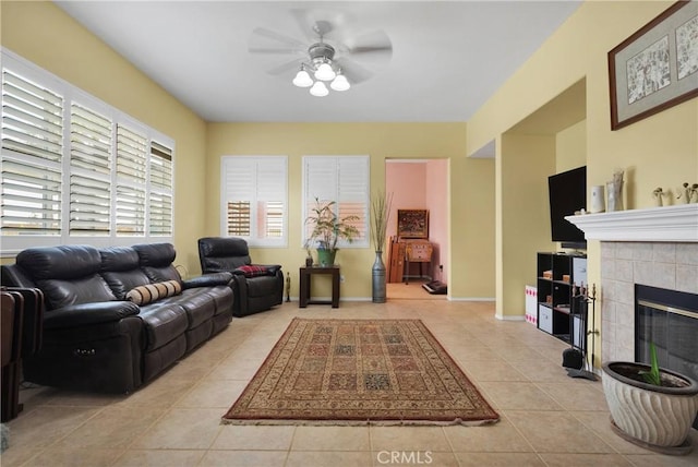 living area featuring a tile fireplace, a ceiling fan, and light tile patterned flooring