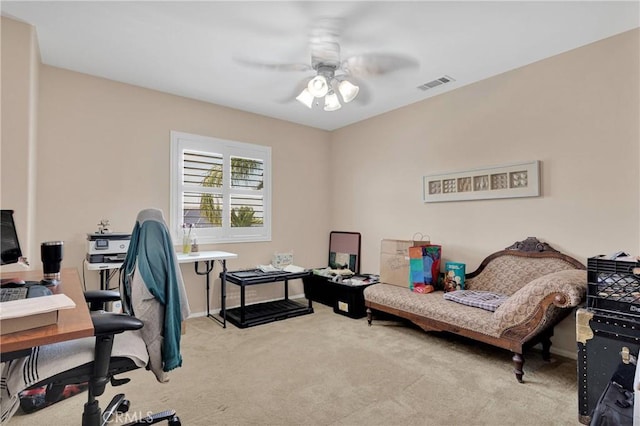 office area with visible vents, baseboards, a ceiling fan, and light colored carpet