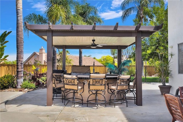 view of patio / terrace featuring grilling area, a fenced backyard, ceiling fan, and outdoor wet bar