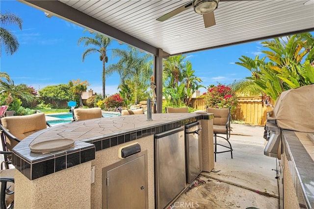 view of patio featuring a fenced in pool, outdoor dry bar, area for grilling, a fenced backyard, and ceiling fan