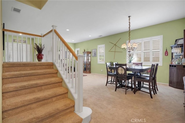 dining space featuring visible vents, light colored carpet, stairway, and an inviting chandelier