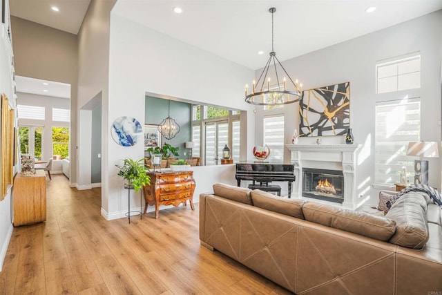 living area featuring baseboards, a wealth of natural light, light wood-type flooring, and a notable chandelier