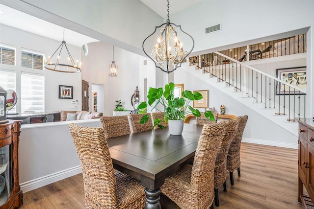 dining room featuring an inviting chandelier, stairway, wood finished floors, and visible vents