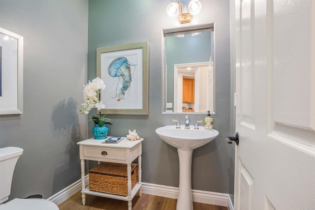 bathroom with toilet, baseboards, a sink, and wood finished floors